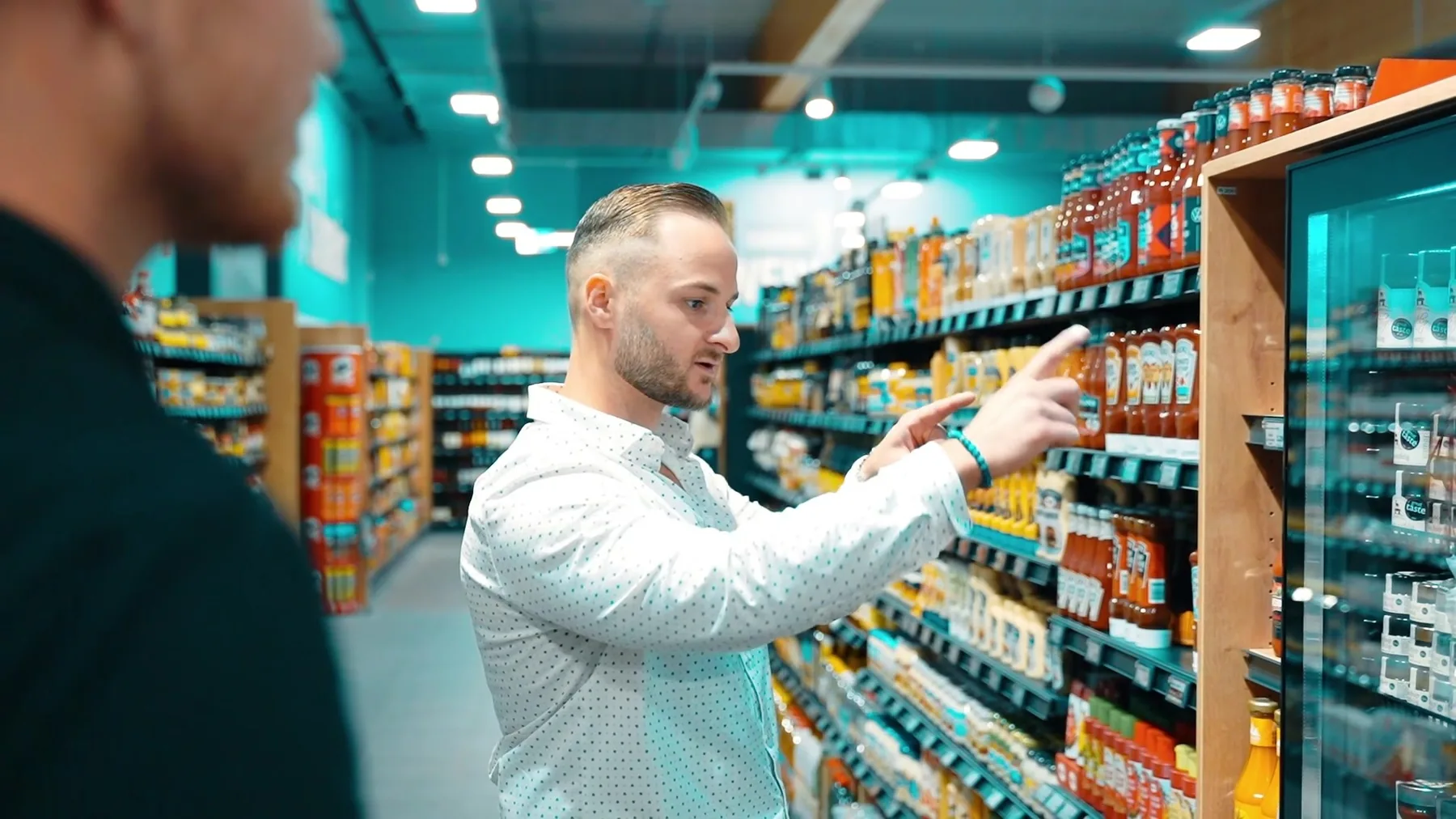 Marcus Strube im Gespräch an einem Regal in einem von SIGMA eingerichteten Markt.