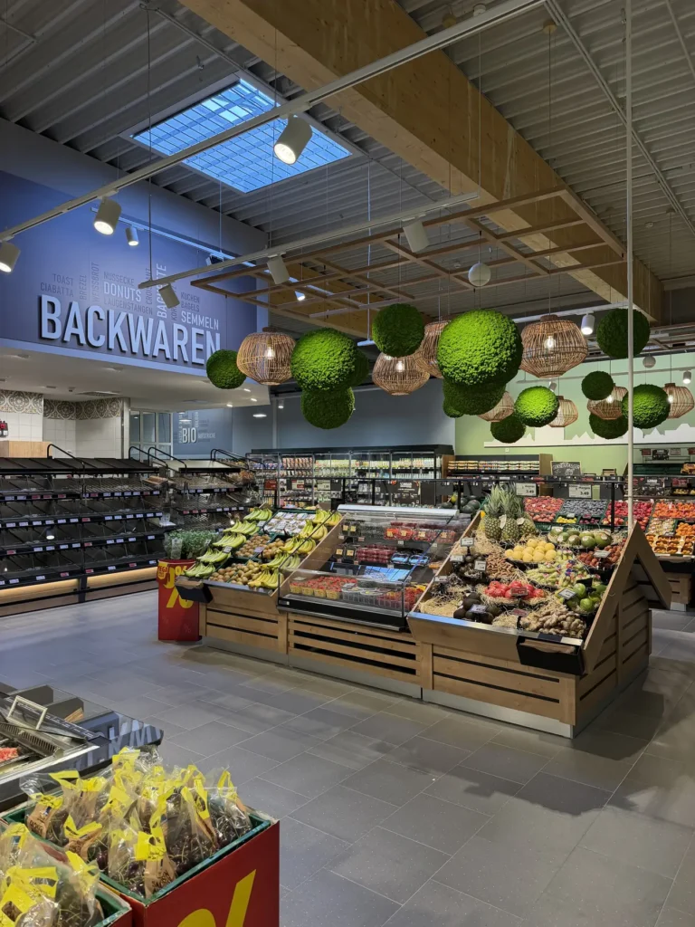 Obst- und Gemüseabteilung mit hängender Kugeldekoration und Trockenfrüchten im Vordergrund