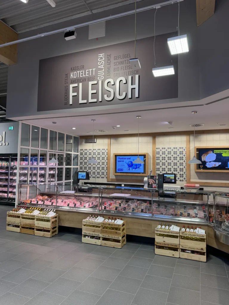 Fleischtheke unter dem Deckenschriftzug »Fleisch« mit Kistenpräsentation
