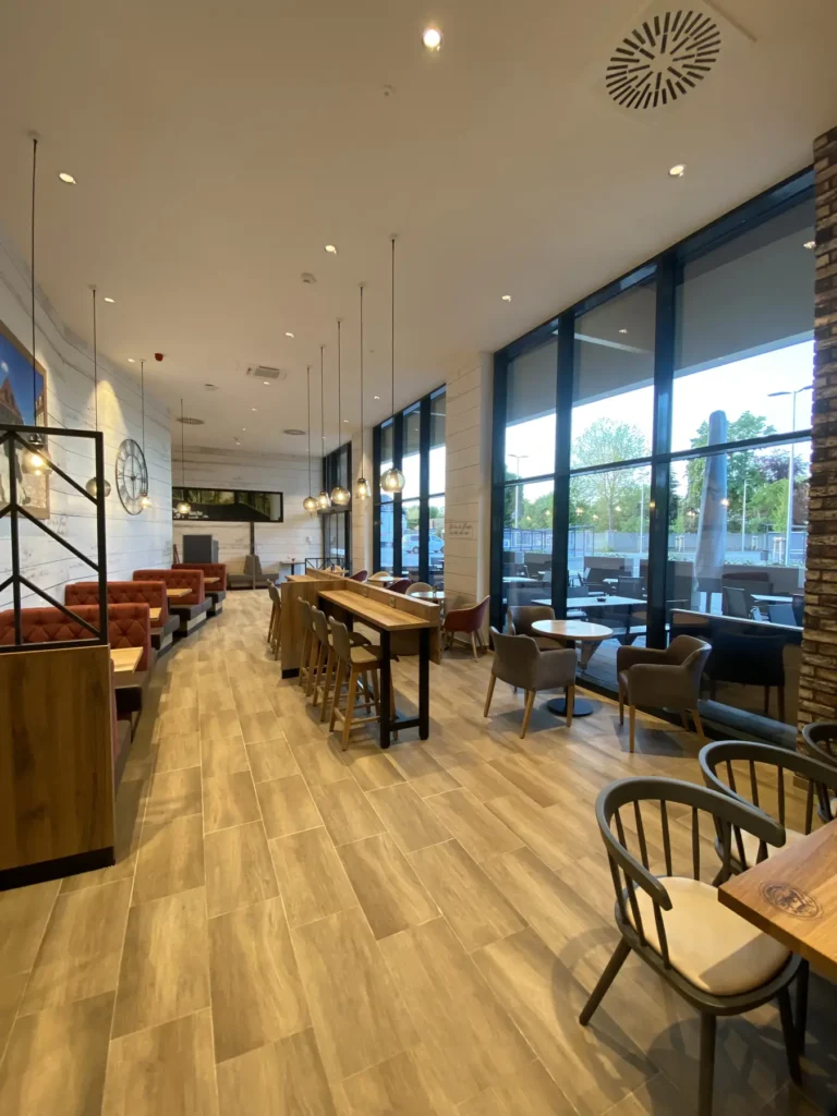 Café-Bereich mit bodentiefen Fenstern und Holzboden