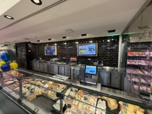 Frischetheke mit Käse und Wurst vor dunkler Fliesenwand