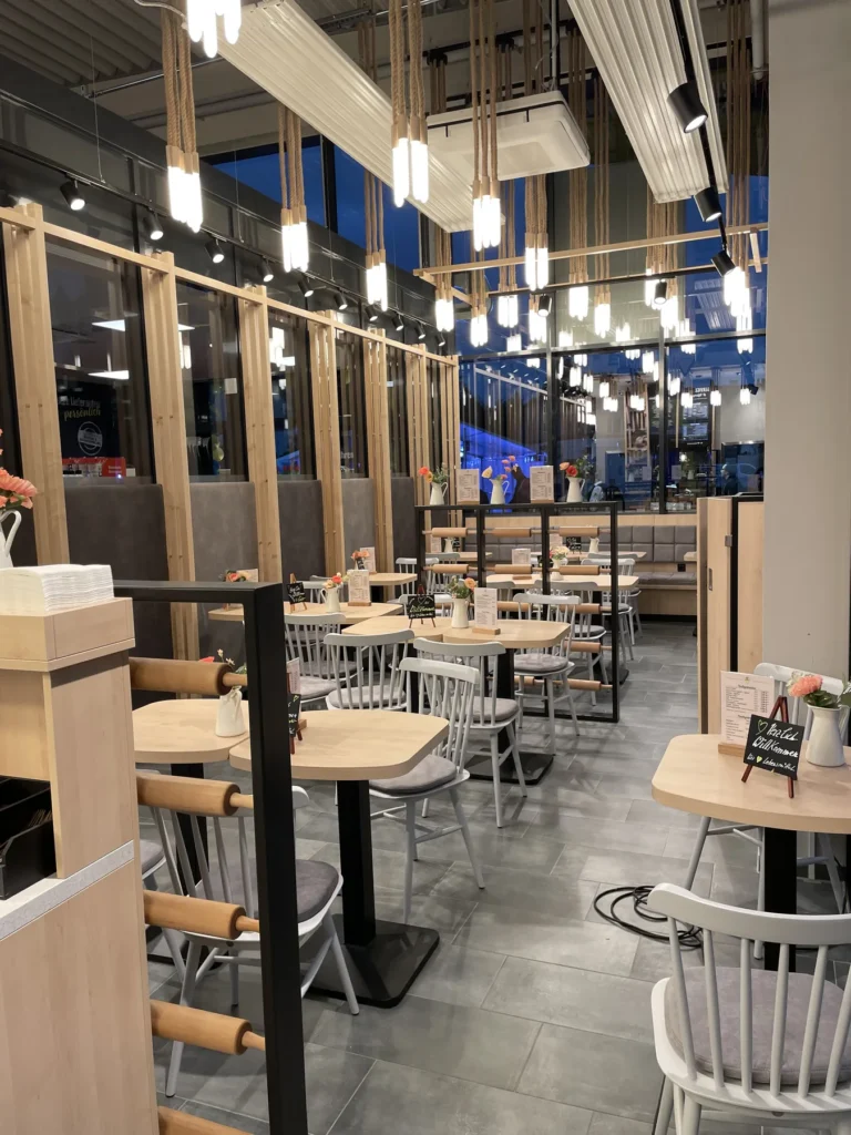 Sitzbereich mit Holztischen und Stühlen neben der Theke