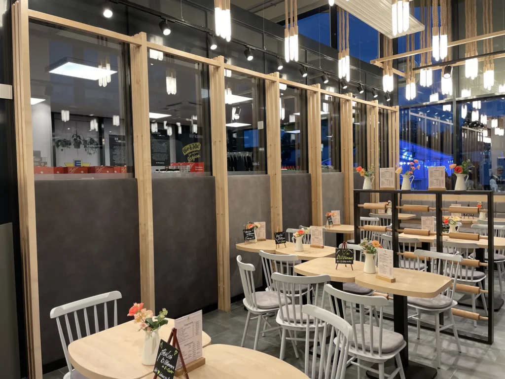 Gastbereich mit Tischen, Stühlen und Glastrennwänden