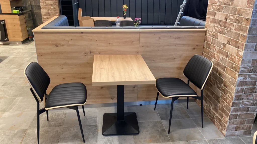 Tisch mit Polsterbank und Stühlen vor Klinkerwand