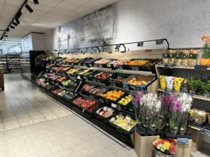 Obst- und Gemüsezeile mit Blumen vor großformatiger Wandgrafik