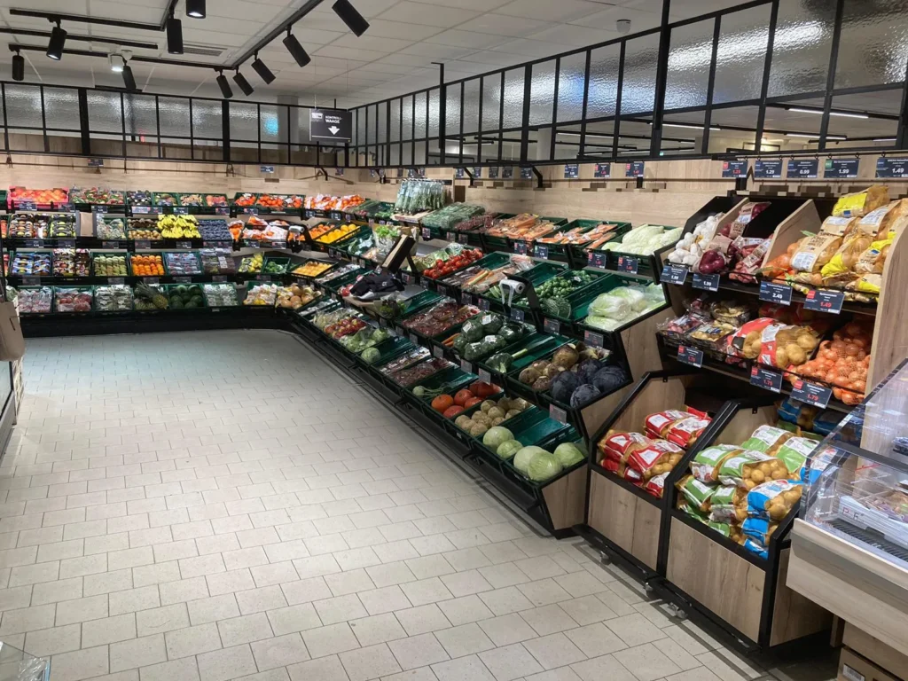 Obst- und Gemüseregal über Eck mit Kühlregal dahinter