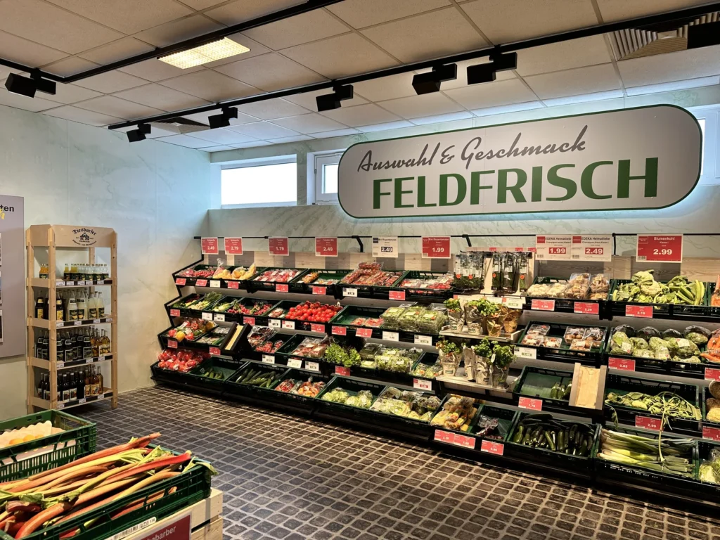 Gemüseregal unter dem Schriftzug »Auswahl & Geschmack — Feldfrisch«