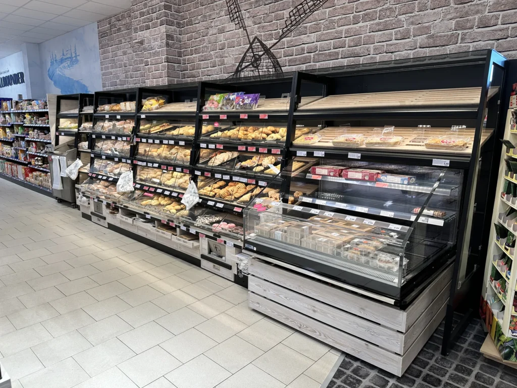 Backstubenregal mit Brot und Brötchen neben der Kühltheke