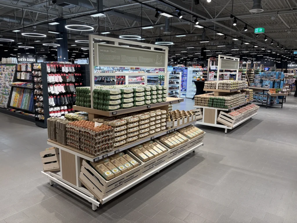 Eierinseln aus Holz mit Kistenaufbau vor dem Drogerie- und Getränkegang